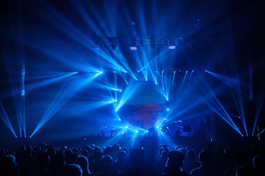 Stage view with blue spotlights. Music show. Silhouettes of the festival. А crowd of fans at the concert. Мusic and light show in the club.